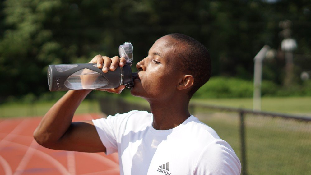 man drinking from gray reusable plastic bottle