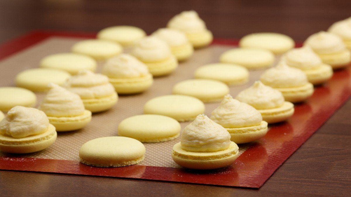 Macaroon halves on a silicone baking mat