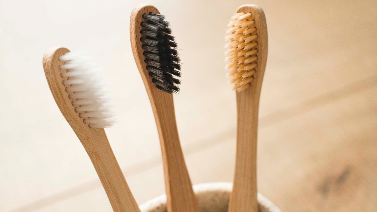 three bamboo toothbrushes on a wooden background