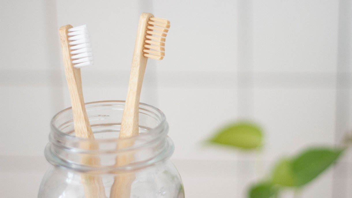 two bamboo toothbrushes in a glass jar