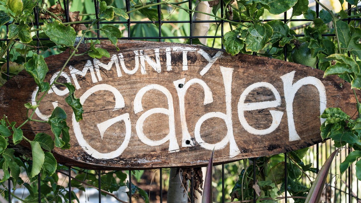 wooden sign that says community harden in white lettering