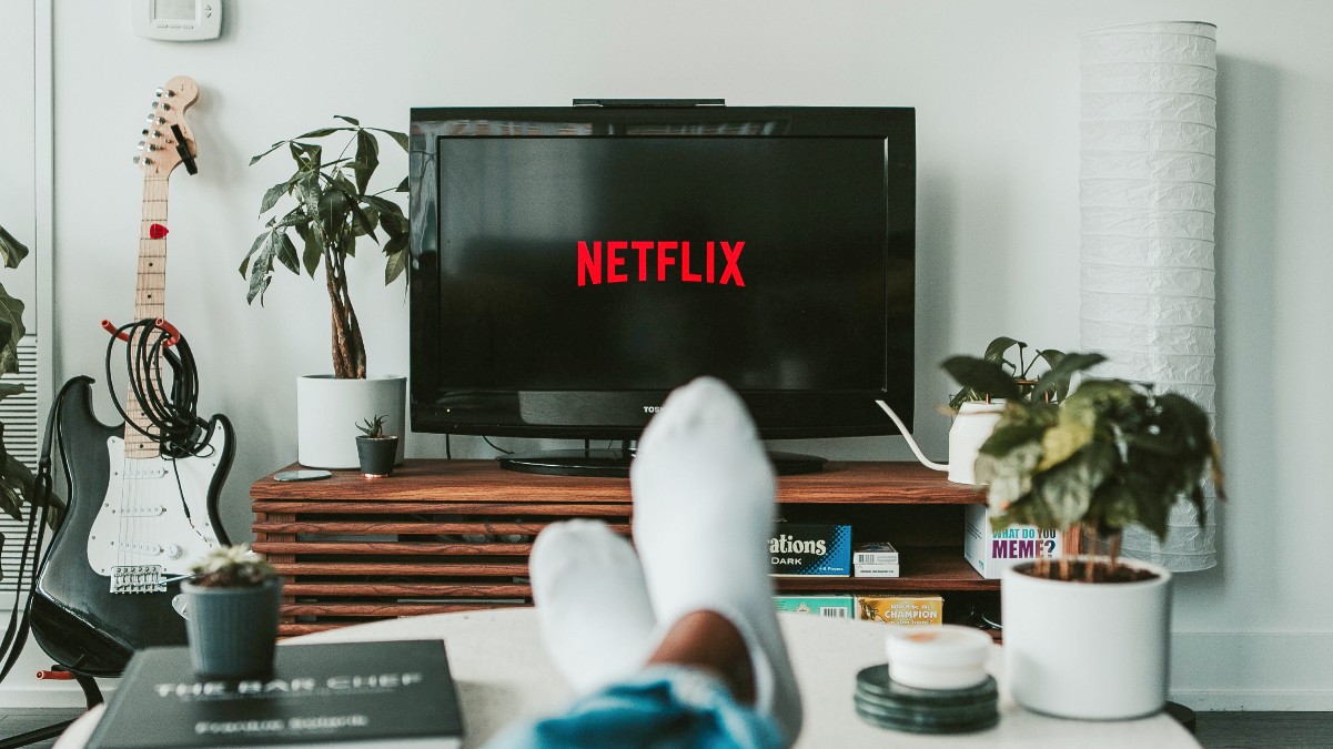 man watching Netflix on TV with his feet up