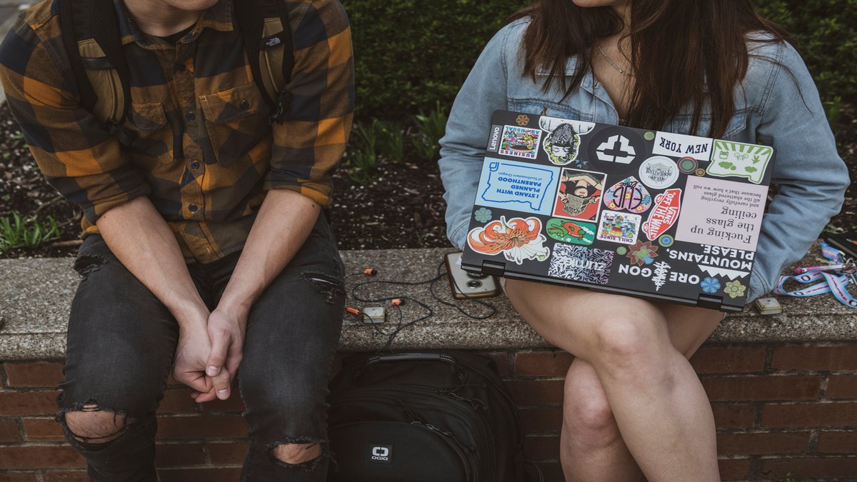 student holds a laptop with a lot of stickers