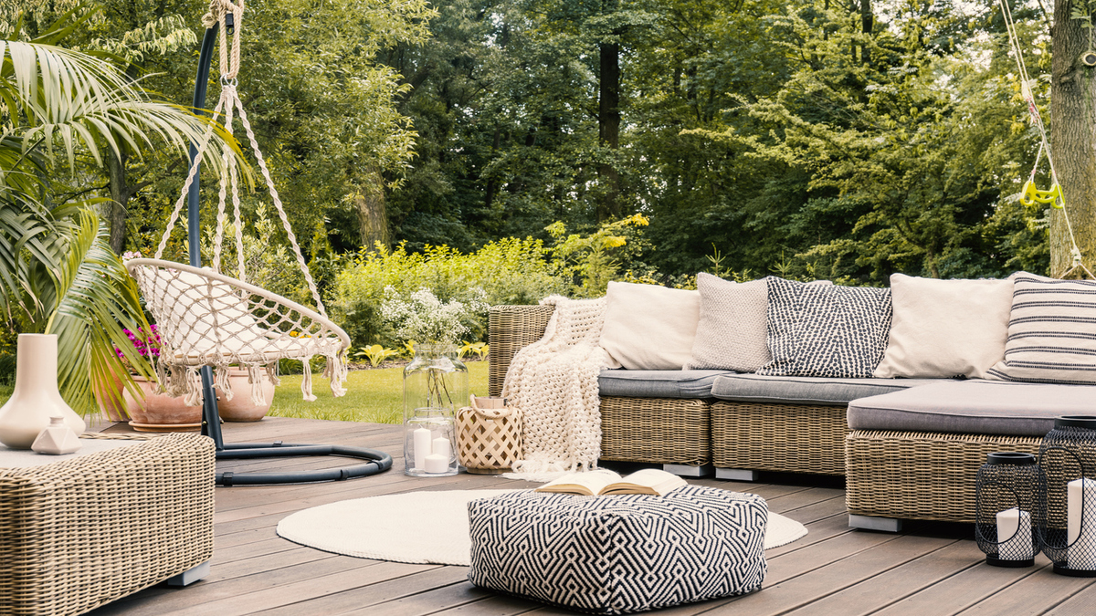 terrace with a rattan furniture: corner sofa, hanging chair and round rug.