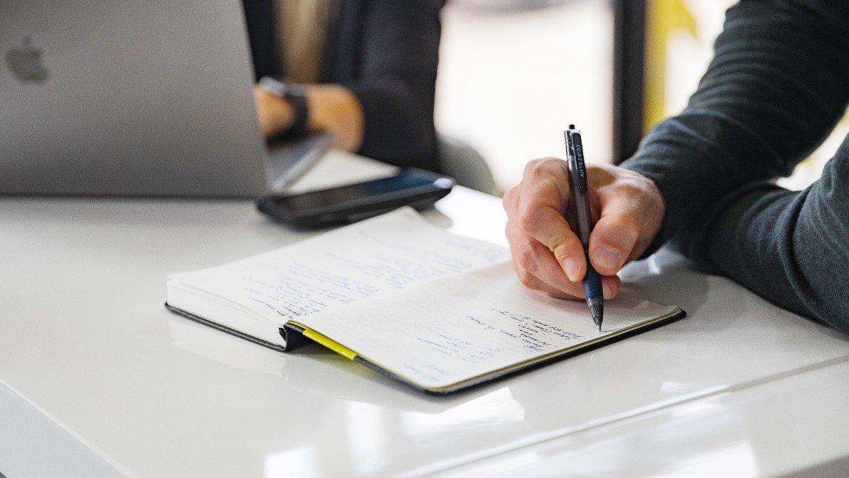 a man writing in a Moleskine notebook